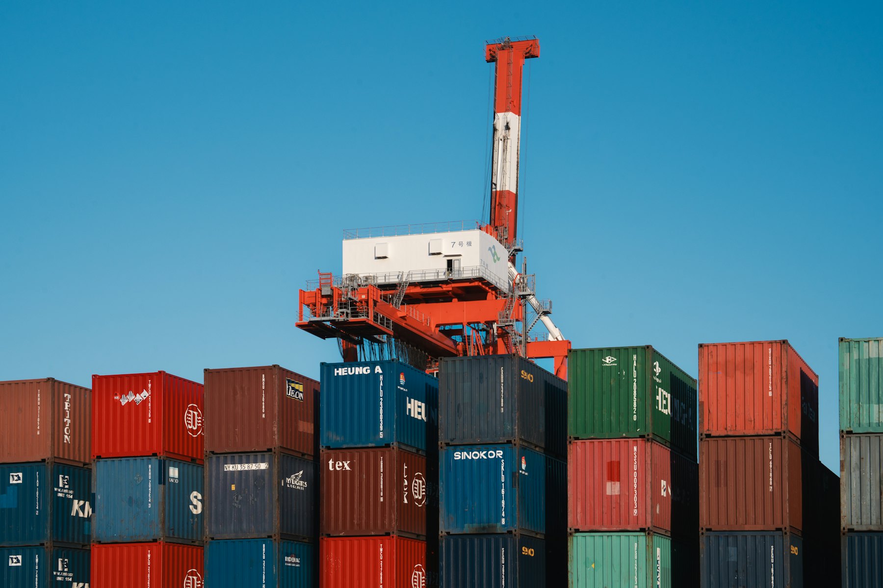 A gantry crane lifting a container above a stack in the yard.